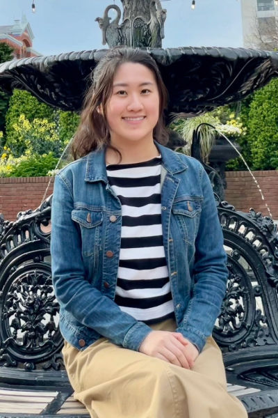Asian woman sitting on a bench outdoors.